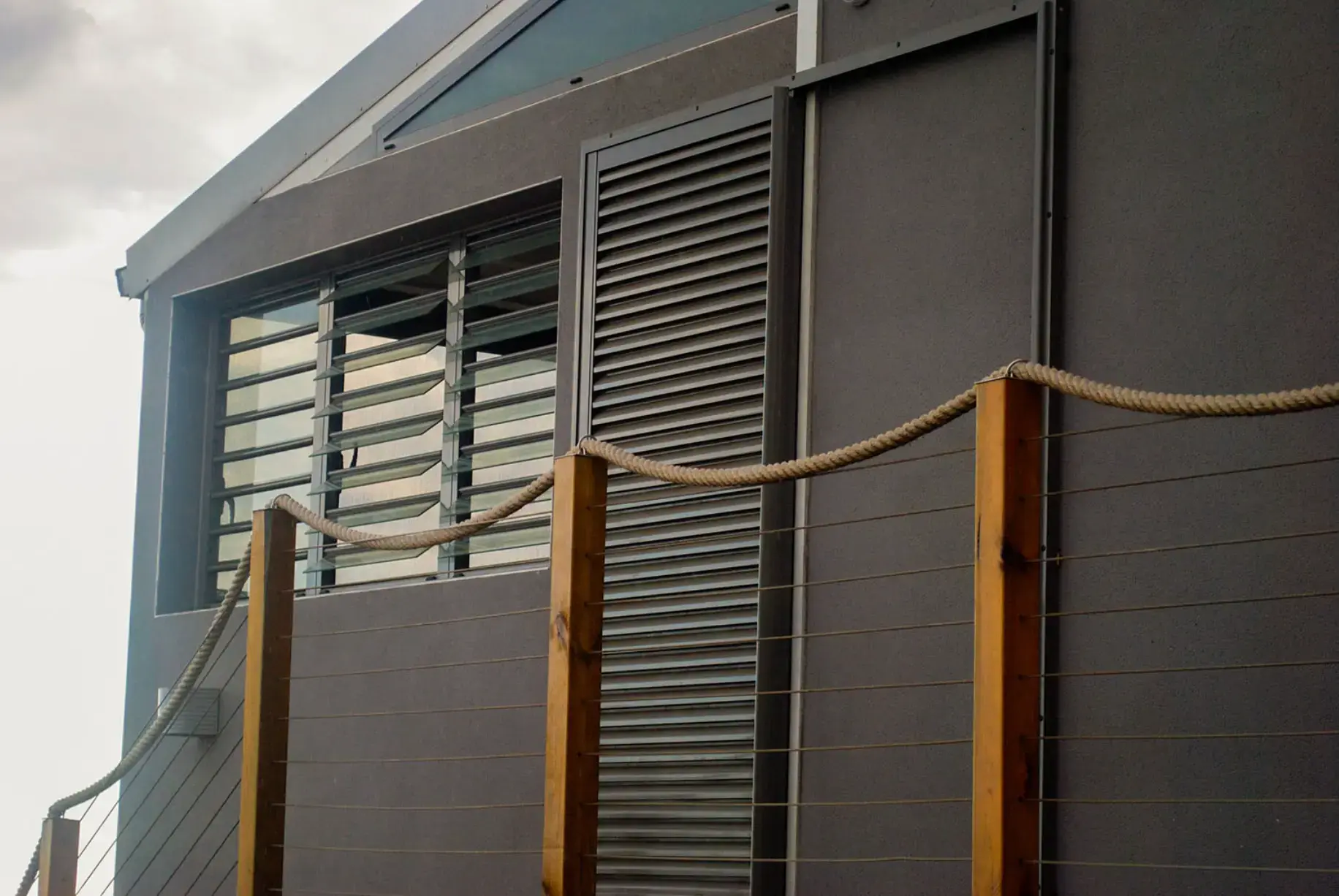 Jalousie vitrée et persienne fixe en aluminium sur une façade grise