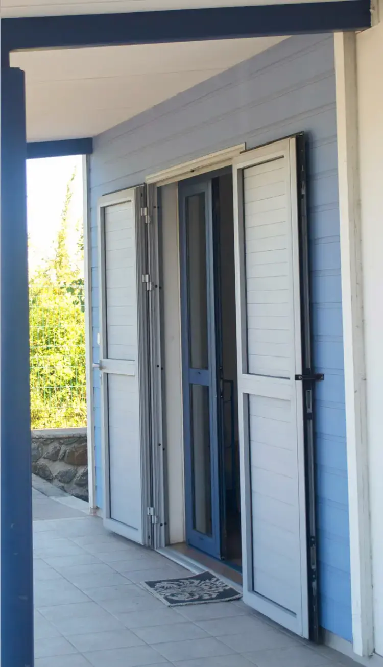 Porte traditionnelle sous véranda avec volets battants bleus intégrés