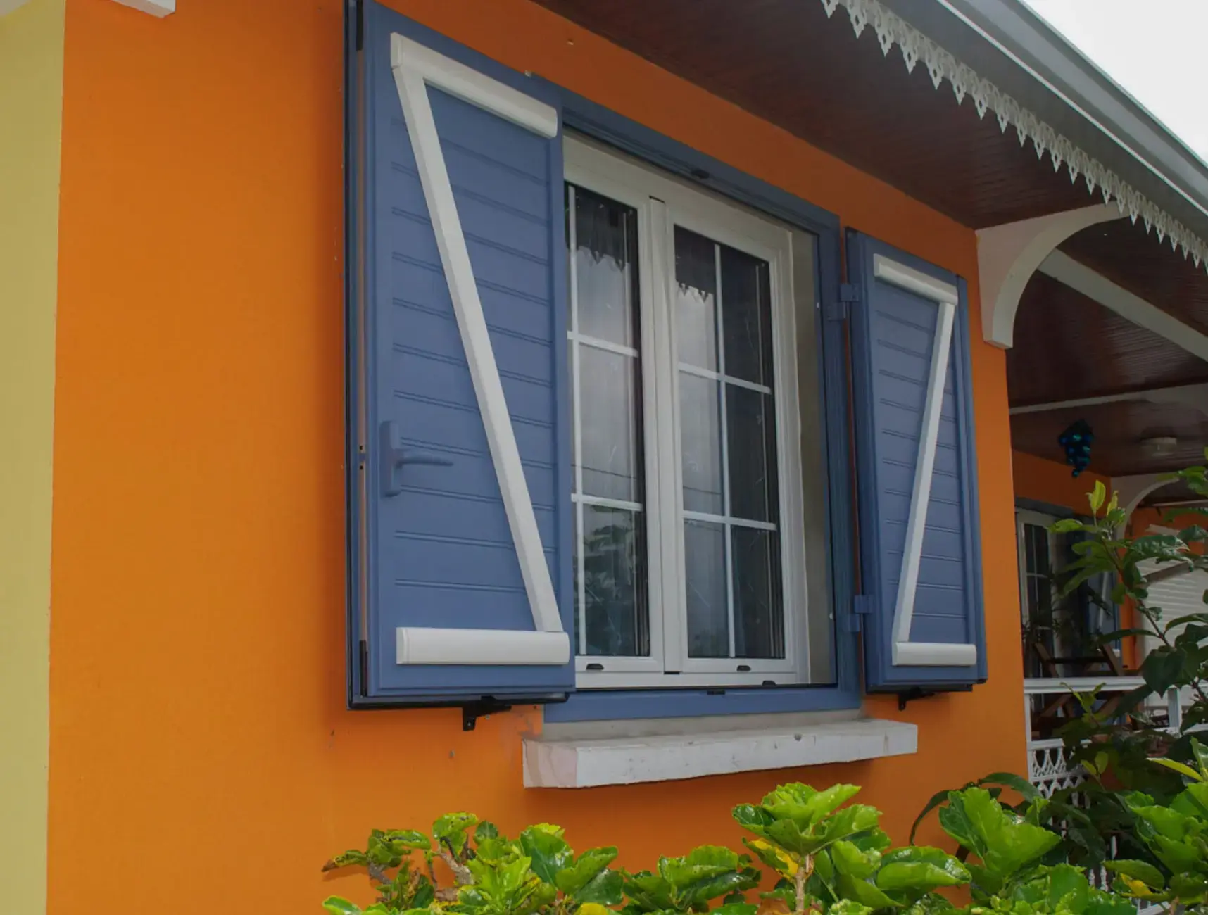 Fenêtre à frappe sur façade orange avec volets battants bleus